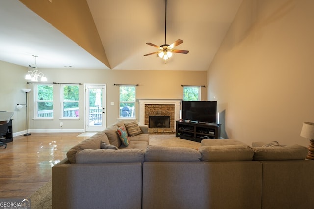 living room featuring a fireplace, ceiling fan with notable chandelier, hardwood / wood-style flooring, and high vaulted ceiling