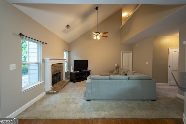 living room featuring a stone fireplace, ceiling fan, hardwood / wood-style floors, and high vaulted ceiling