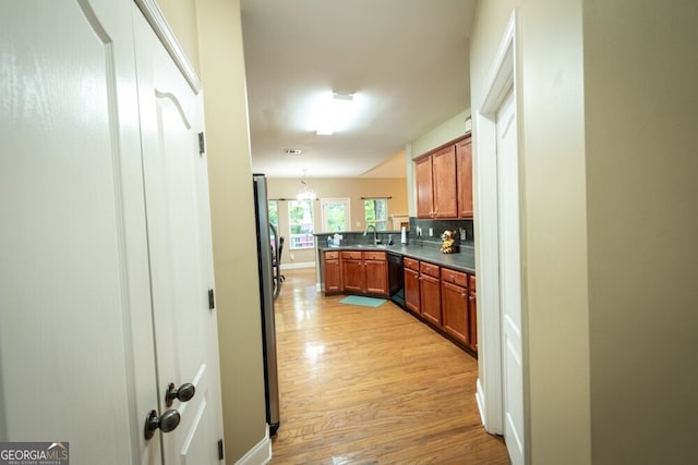 kitchen with backsplash, light hardwood / wood-style flooring, sink, black dishwasher, and pendant lighting