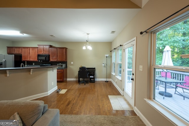 kitchen featuring a notable chandelier, tasteful backsplash, wood-type flooring, hanging light fixtures, and stainless steel fridge with ice dispenser