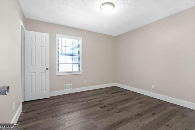 empty room featuring dark wood-type flooring and a textured ceiling