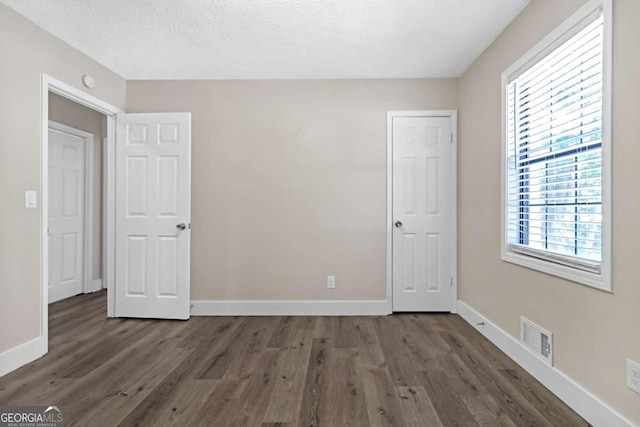 unfurnished room featuring dark hardwood / wood-style floors and a textured ceiling