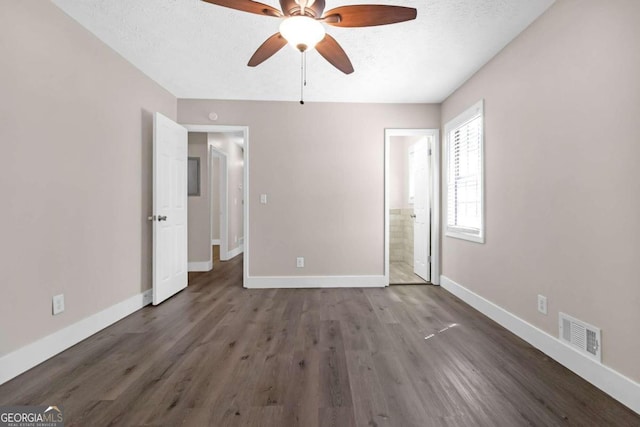 unfurnished bedroom with ceiling fan, dark hardwood / wood-style floors, ensuite bathroom, and a textured ceiling