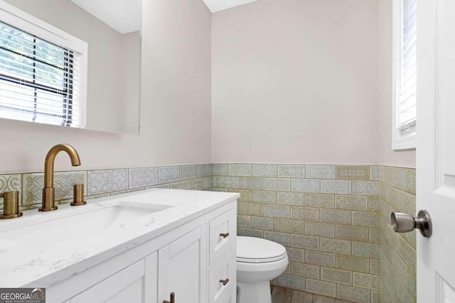 bathroom with vanity, toilet, wood-type flooring, and tile walls