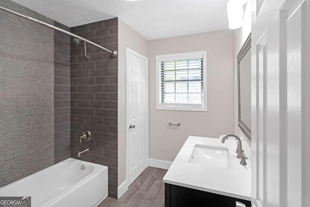 bathroom with tiled shower / bath, hardwood / wood-style flooring, a textured ceiling, and vanity