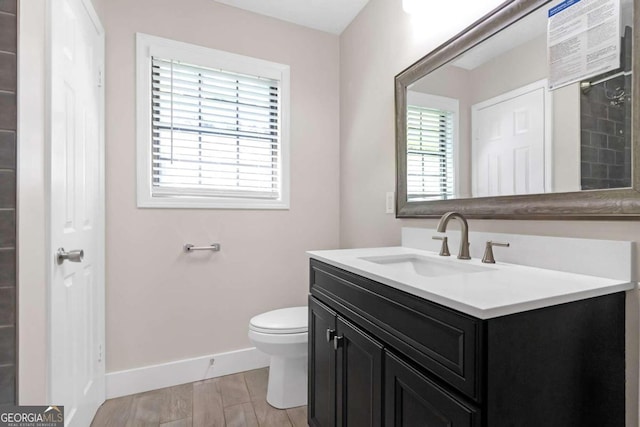 bathroom with a healthy amount of sunlight, toilet, vanity, and wood-type flooring