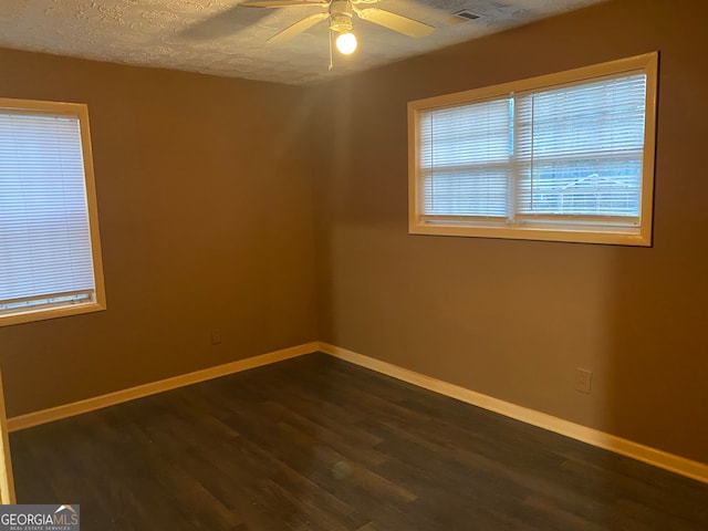 empty room featuring a textured ceiling, dark wood-type flooring, and ceiling fan