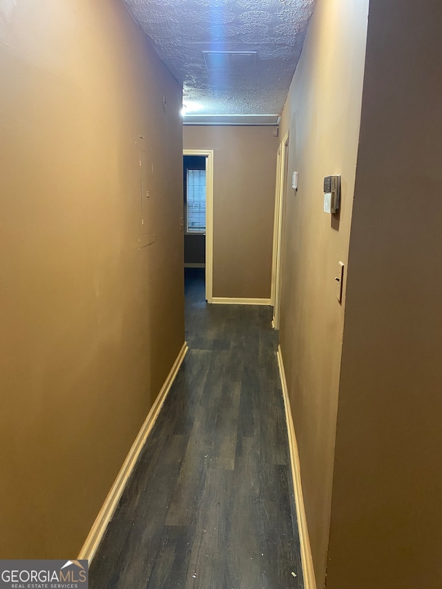 hallway with dark wood-type flooring and a textured ceiling