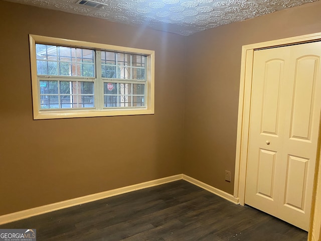 empty room with dark hardwood / wood-style flooring and a textured ceiling