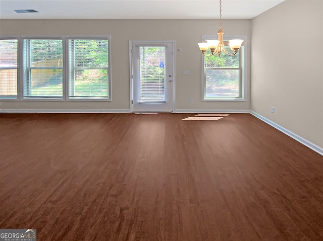 empty room featuring an inviting chandelier and dark hardwood / wood-style flooring