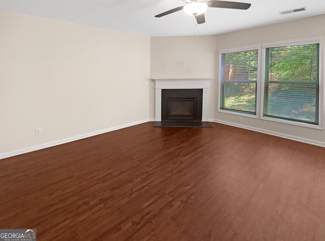 unfurnished living room featuring dark wood-type flooring and ceiling fan