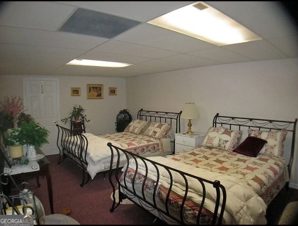 carpeted bedroom featuring a drop ceiling