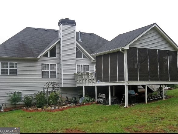 rear view of house featuring a yard and a sunroom