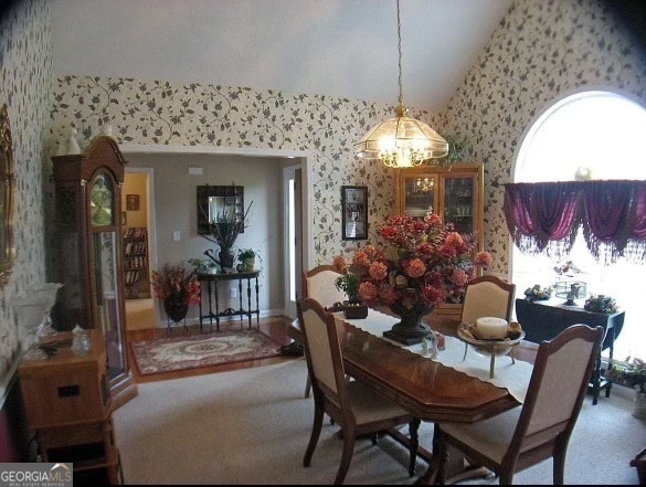 carpeted dining space with high vaulted ceiling and a notable chandelier