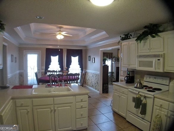 kitchen featuring ornamental molding, white appliances, sink, ceiling fan, and a raised ceiling