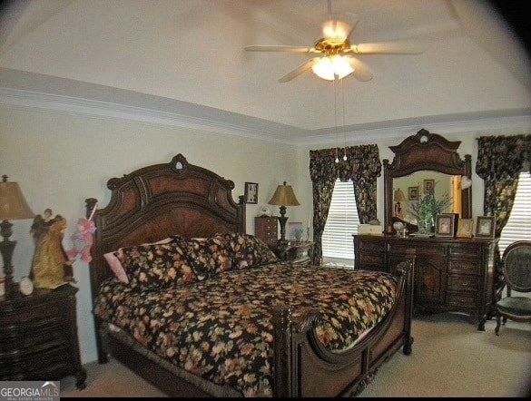 bedroom with carpet flooring, a tray ceiling, ceiling fan, and ornamental molding