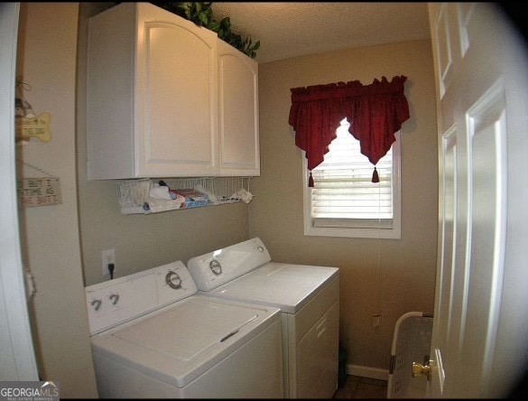 laundry room featuring a textured ceiling, cabinets, and separate washer and dryer