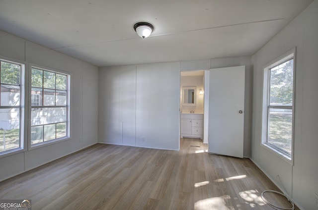 unfurnished bedroom with light wood-style floors and ensuite bath