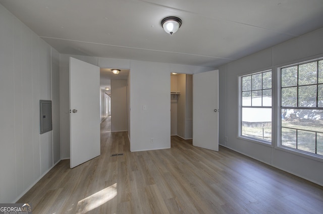 unfurnished bedroom featuring a spacious closet, electric panel, visible vents, and light wood-type flooring