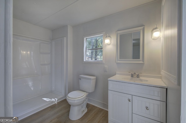 bathroom featuring baseboards, walk in shower, toilet, wood finished floors, and vanity