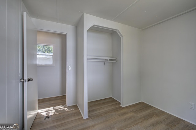 unfurnished bedroom featuring visible vents, a closet, and wood finished floors