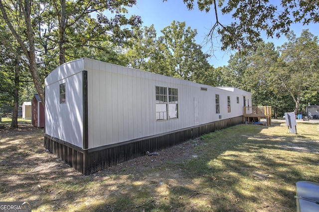 view of side of property featuring a lawn and a wooden deck