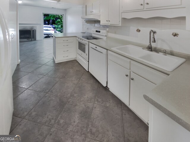 kitchen with white appliances, decorative backsplash, white cabinetry, and sink