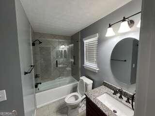 full bathroom with tile patterned flooring, vanity, toilet, and enclosed tub / shower combo