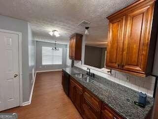 kitchen with dark stone counters, a textured ceiling, and wood-type flooring