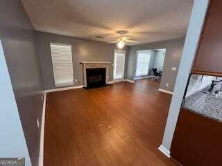 unfurnished living room featuring ceiling fan and dark hardwood / wood-style floors