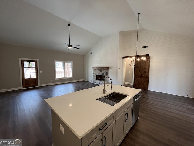 kitchen featuring stainless steel dishwasher, a stone fireplace, sink, and a center island with sink