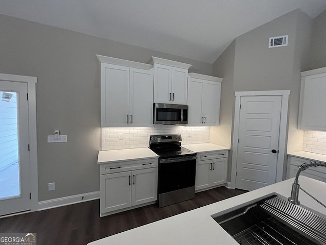 kitchen with vaulted ceiling, appliances with stainless steel finishes, sink, and white cabinets