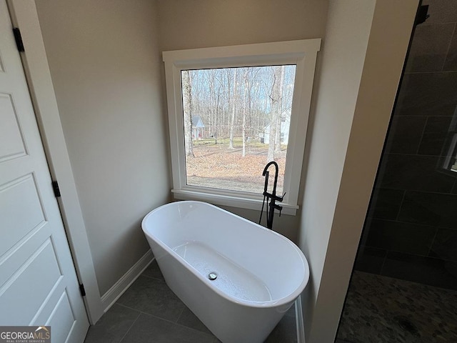 bathroom with tile patterned flooring, a wealth of natural light, and a washtub