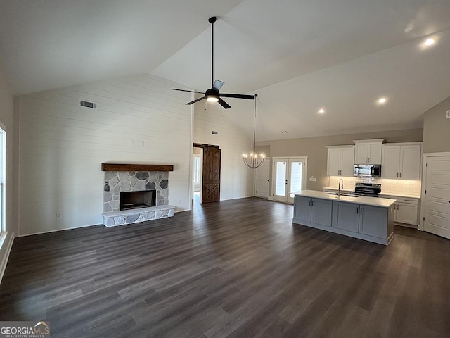 kitchen featuring white cabinetry, stainless steel appliances, dark hardwood / wood-style floors, a center island with sink, and a barn door