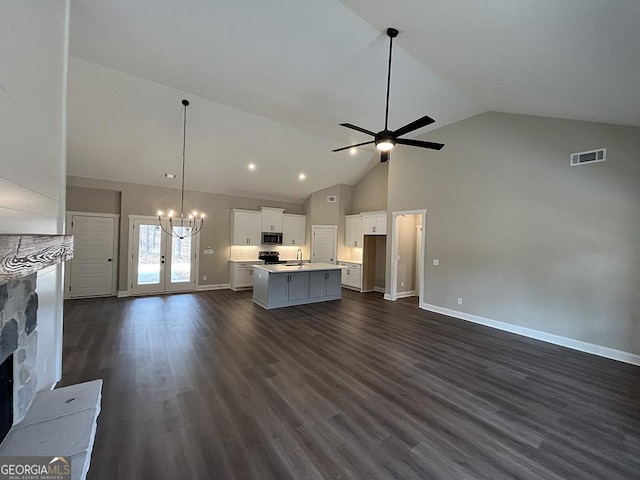 unfurnished living room with dark wood-type flooring, sink, high vaulted ceiling, a fireplace, and ceiling fan with notable chandelier