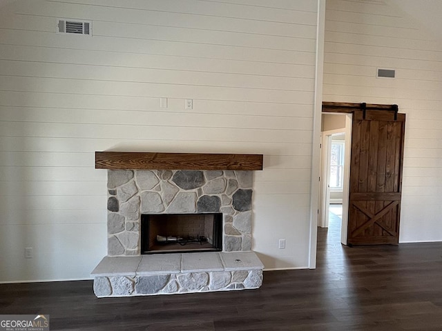 interior details featuring hardwood / wood-style flooring, a fireplace, a barn door, and wooden walls