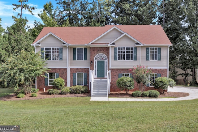 raised ranch featuring a front yard and brick siding