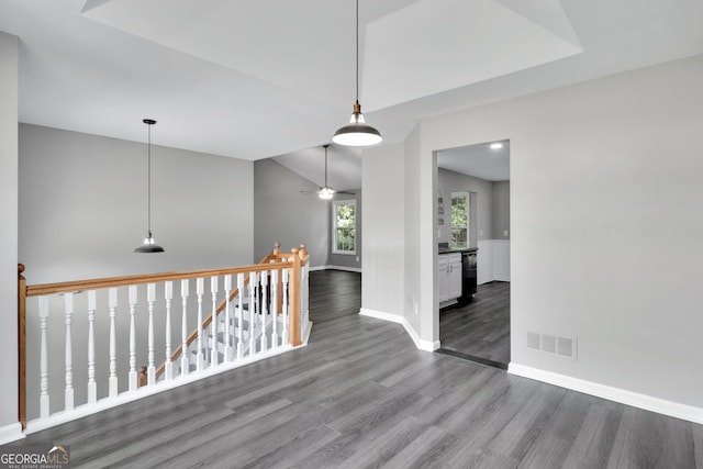 hall featuring lofted ceiling, wood finished floors, visible vents, an upstairs landing, and baseboards