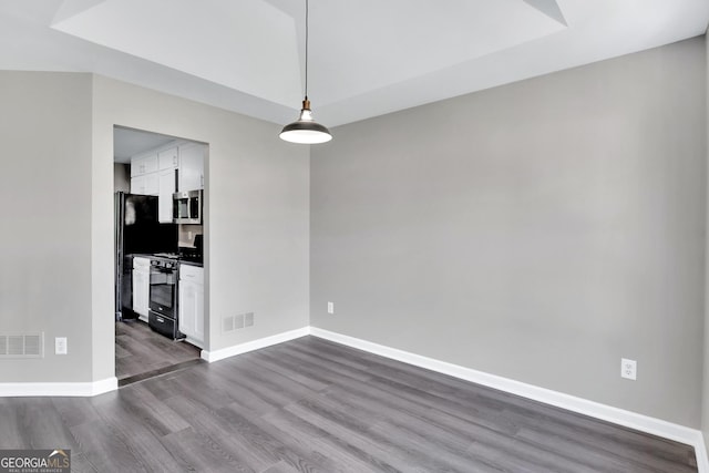 unfurnished dining area featuring dark wood-type flooring, visible vents, and baseboards