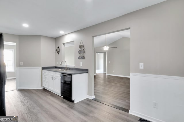 kitchen with dishwasher, dark countertops, wood finished floors, white cabinetry, and a sink