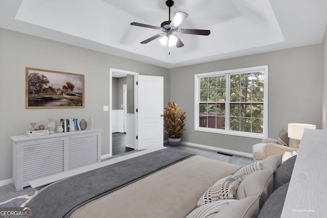 bedroom featuring visible vents, baseboards, ceiling fan, carpet, and a tray ceiling