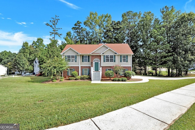 split foyer home featuring a front yard and brick siding