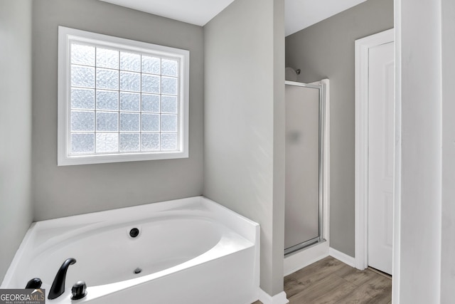 bathroom featuring a garden tub, a shower stall, and wood finished floors