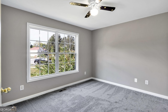 spare room featuring carpet floors, baseboards, visible vents, and a ceiling fan