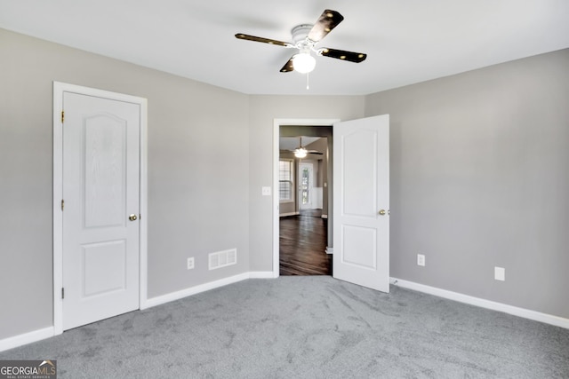 unfurnished bedroom with a ceiling fan, baseboards, visible vents, and carpet flooring