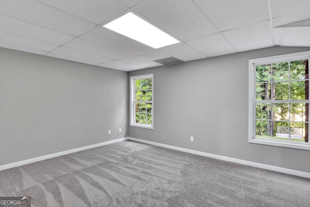 carpeted spare room featuring a paneled ceiling and baseboards