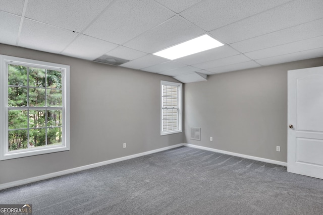 carpeted spare room featuring visible vents, baseboards, and a drop ceiling