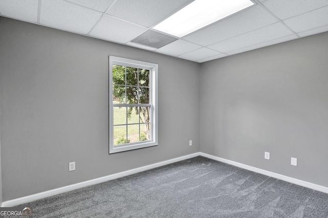 empty room with a drop ceiling, dark carpet, and baseboards