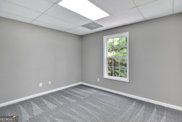 carpeted spare room with a paneled ceiling and baseboards