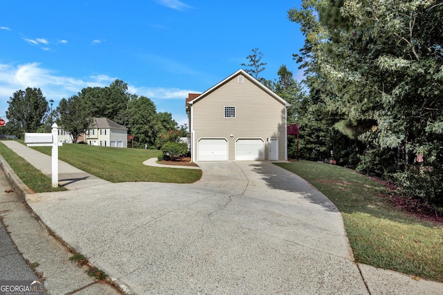 view of side of property featuring a yard, driveway, and an attached garage